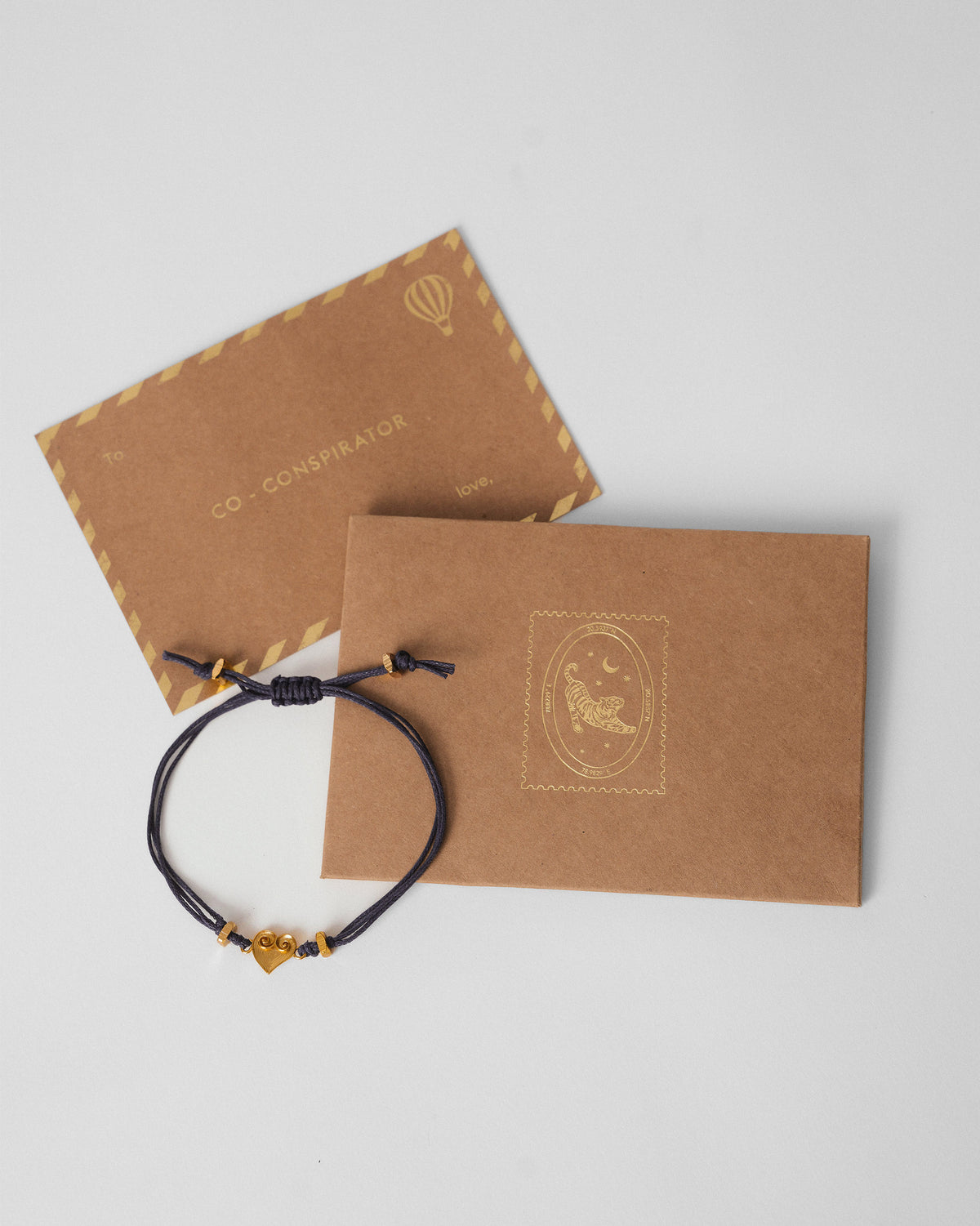 Blue Dil Rakhi beside a kraft gift envelope and card.