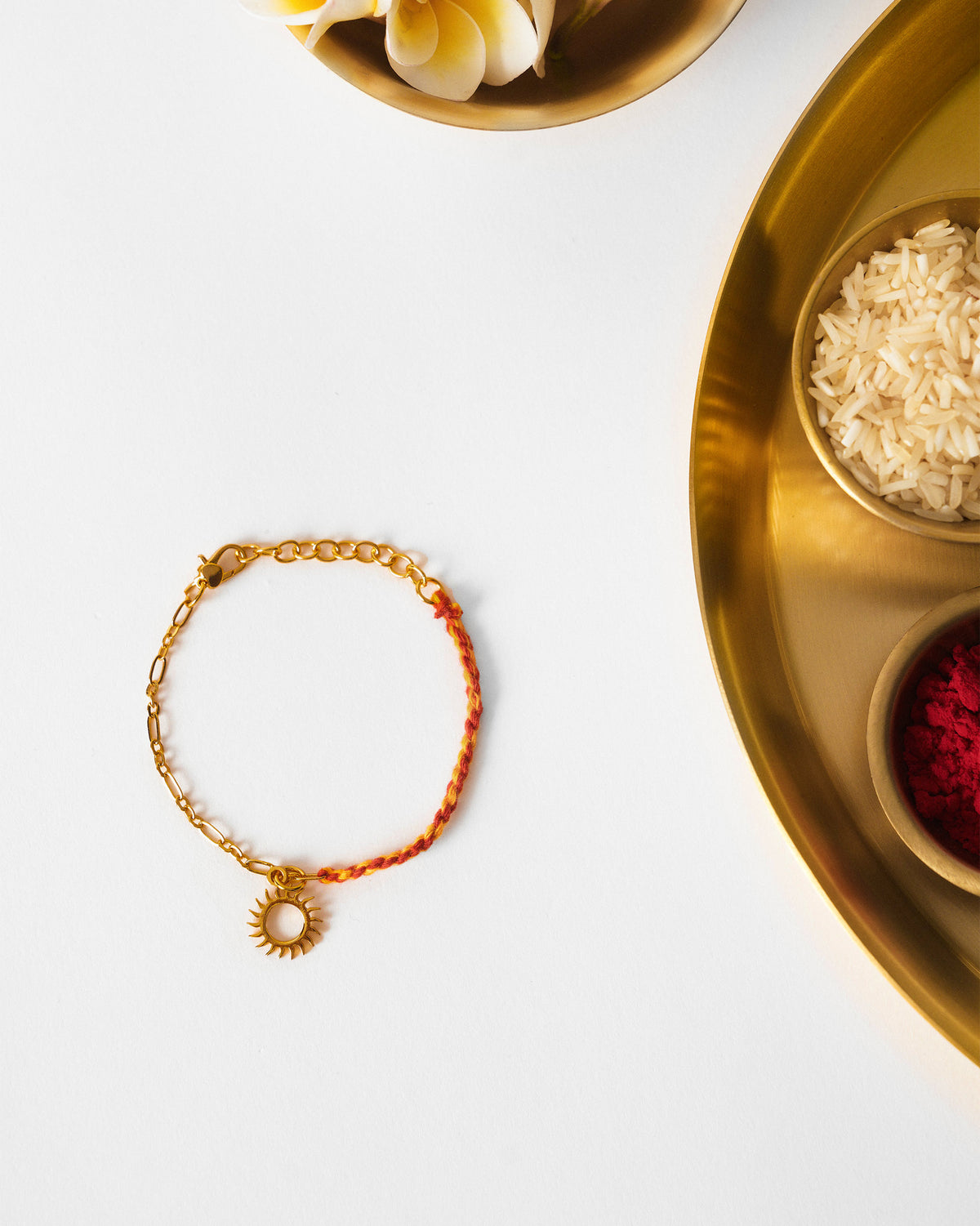 Gold and red Sun Charmlet laid flat on a white surface.