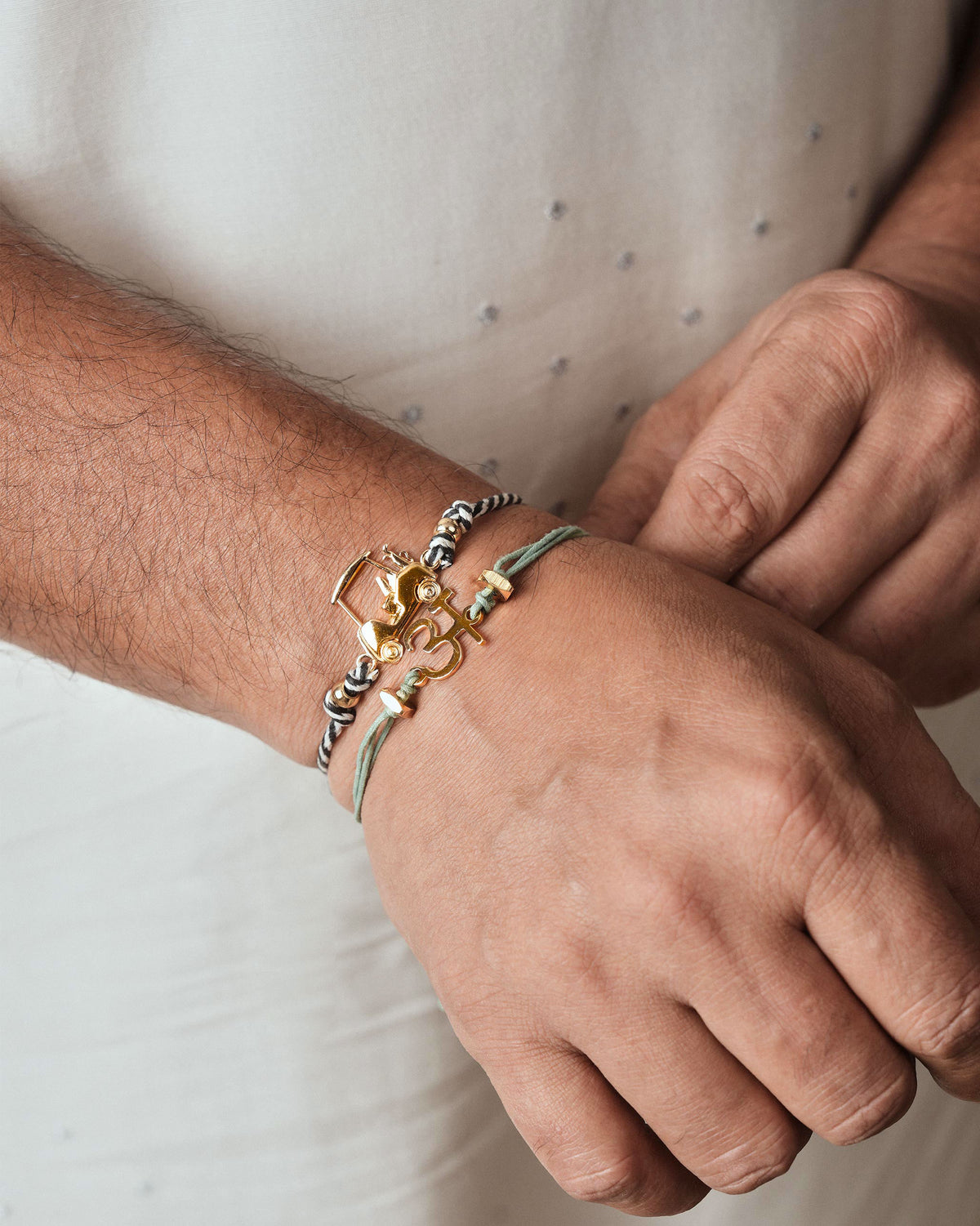 Aqua alphabet rakhi with a gold letter charm worn on a wrist.