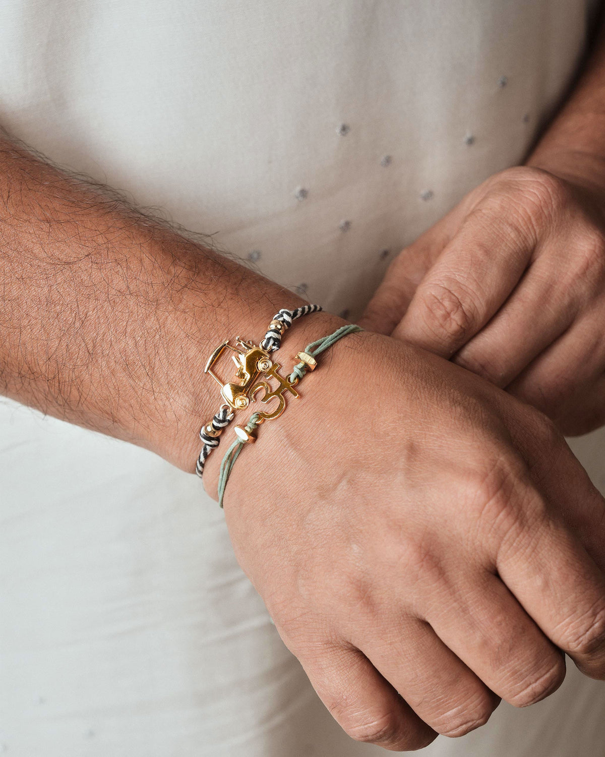 Gold charm rakhis worn stacked on a wrist.