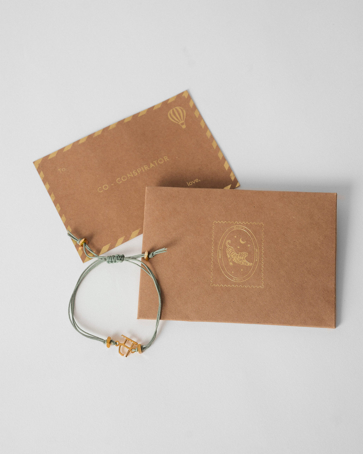 Alphabet S rakhi resting on kraft gift envelopes.