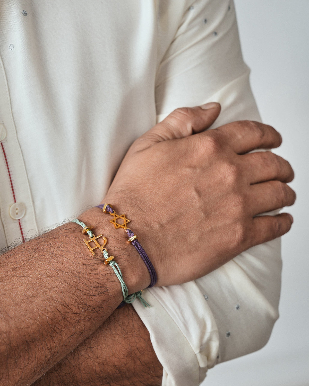 Alphabet S rakhi worn on a wrist with another cord bracelet.