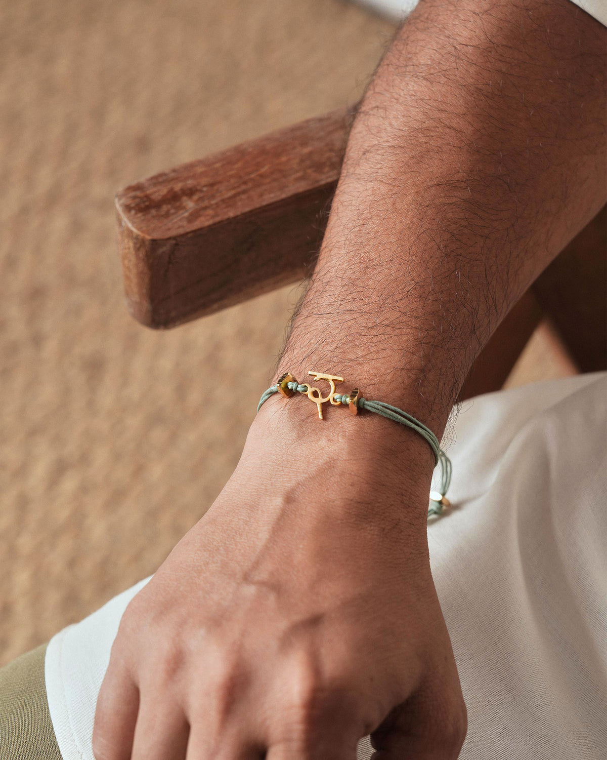 Person wearing Alphabet R Rakhi in green cord on the wrist.