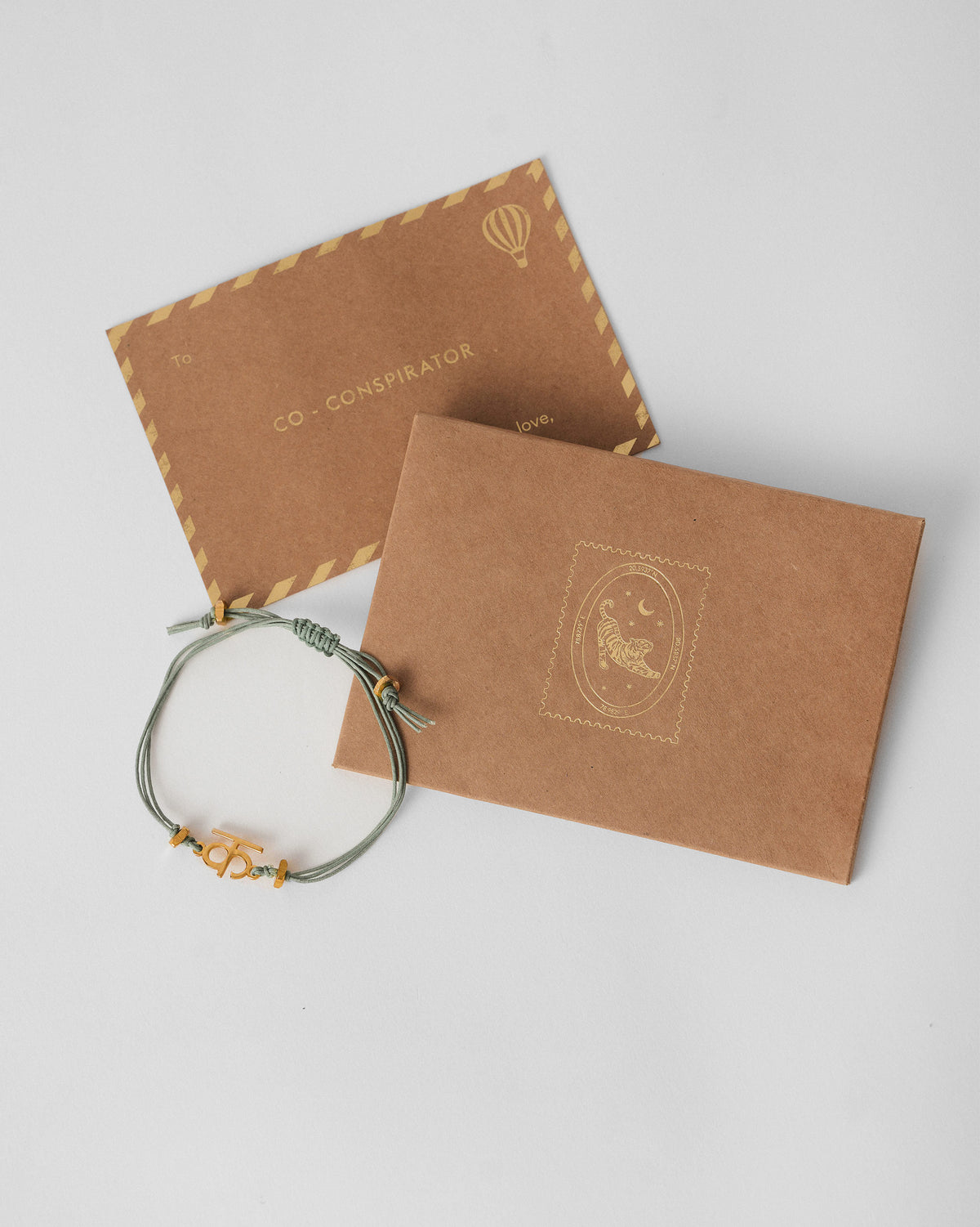 Alphabet K Rakhi beside a kraft envelope and card.