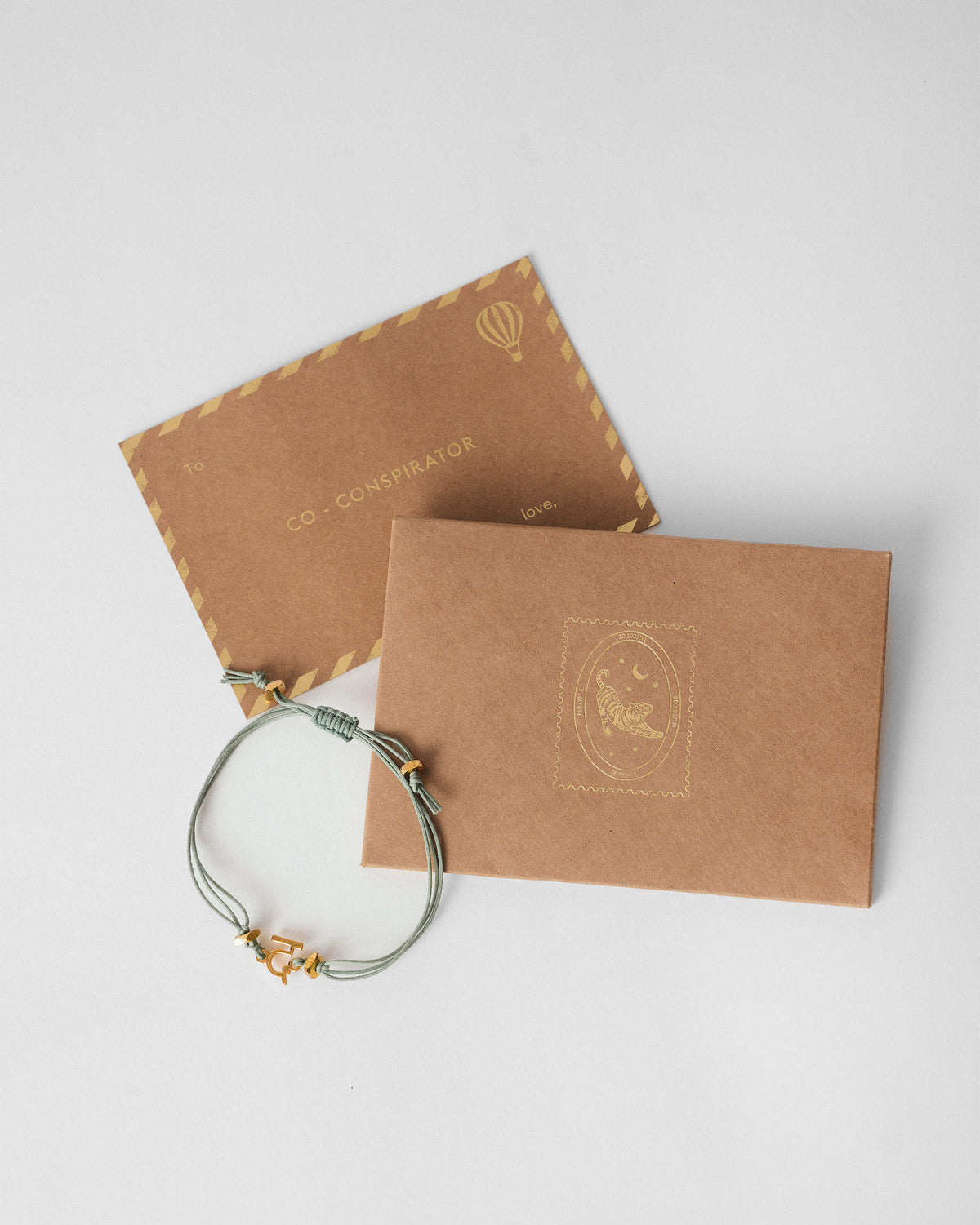 Alphabet D Rakhi beside a kraft envelope and card.