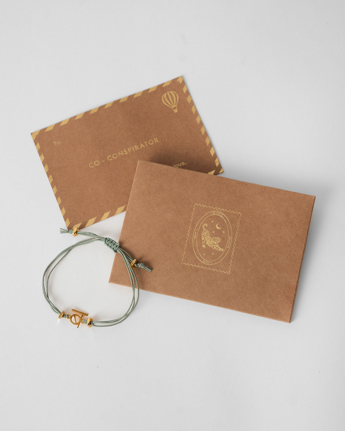 Alphabet B Rakhi beside a kraft envelope and card.