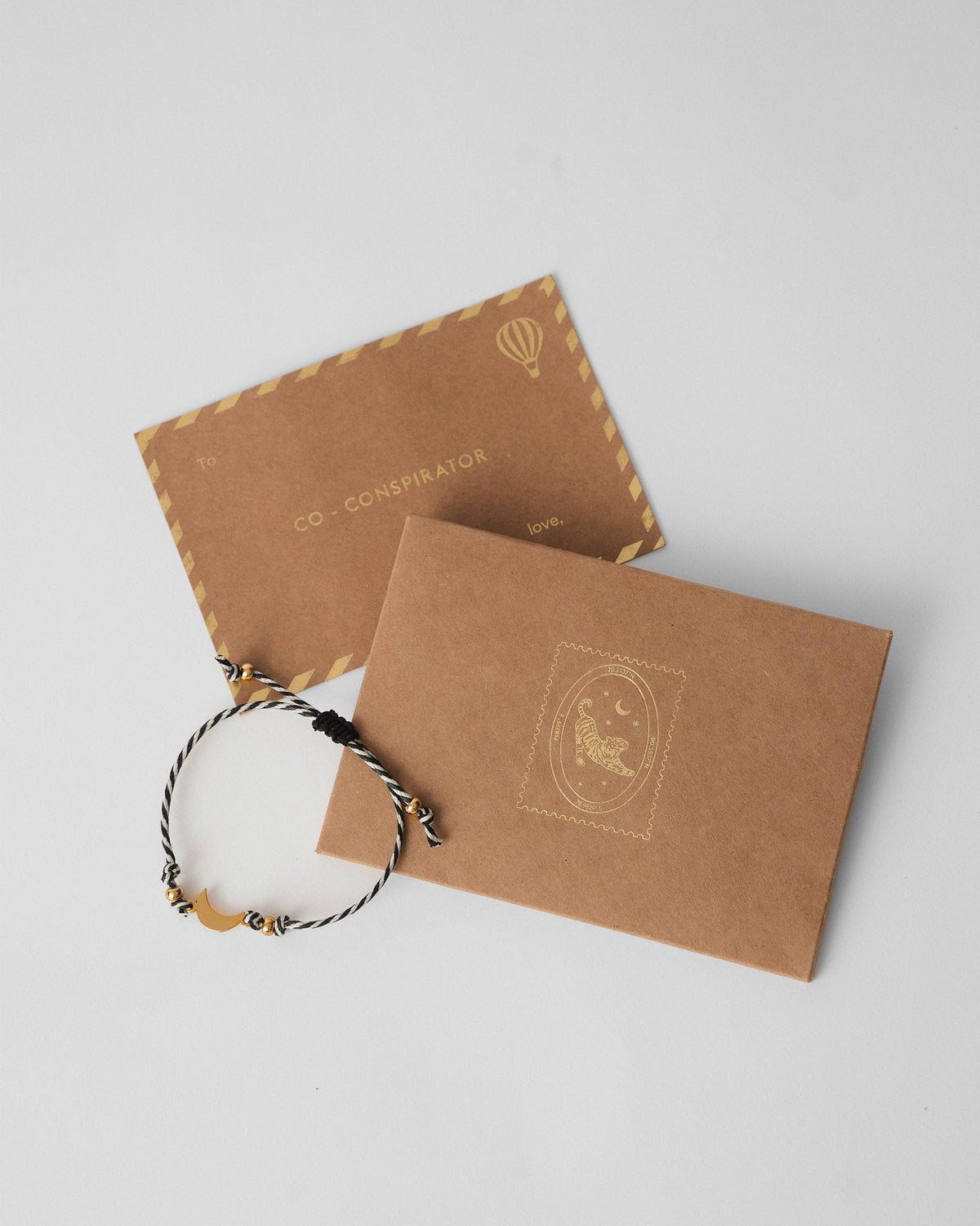 Chand Rakhi with a gold crescent charm laid beside kraft envelopes.