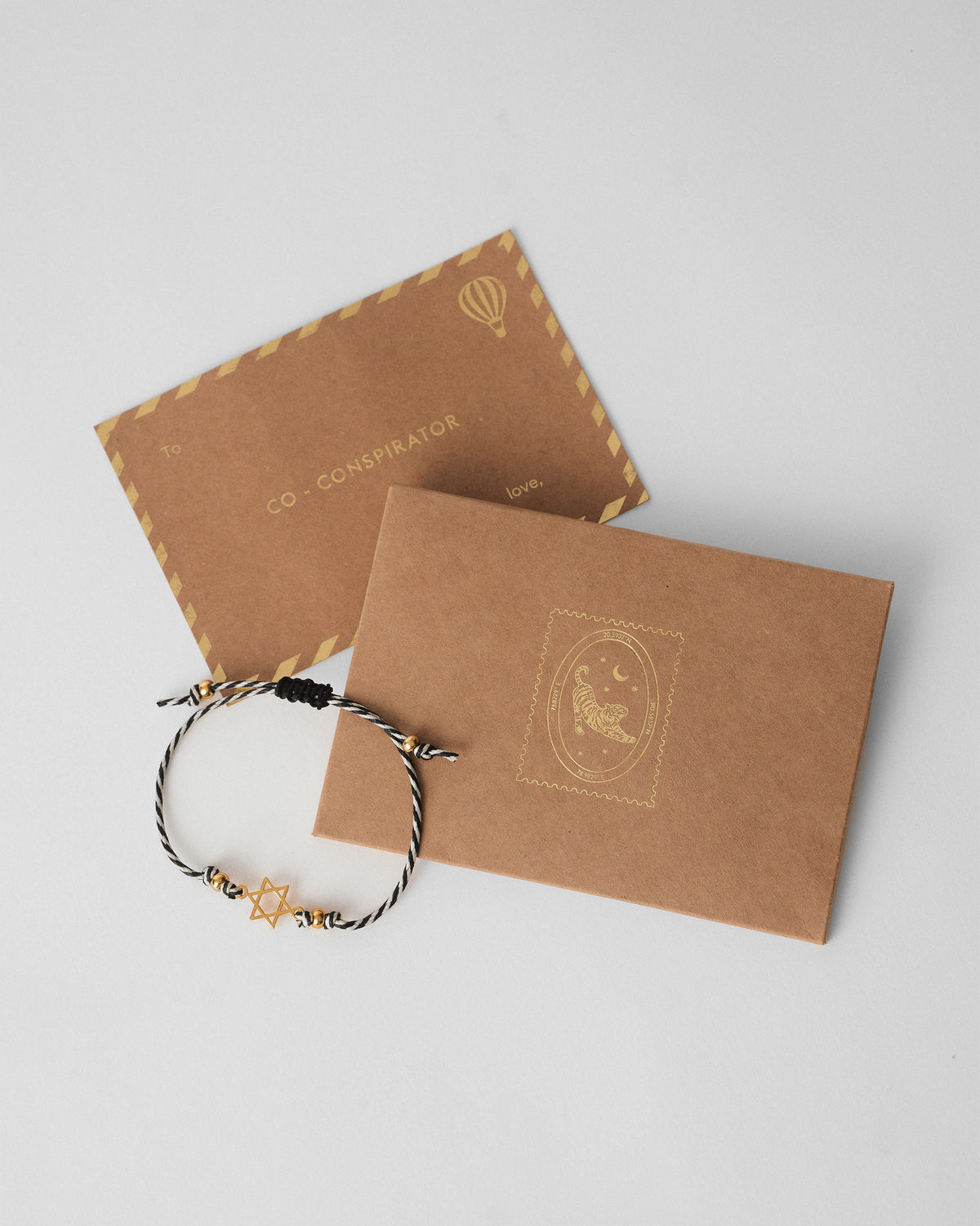 Sitara Rakhi with a gold star laid over a kraft envelope.