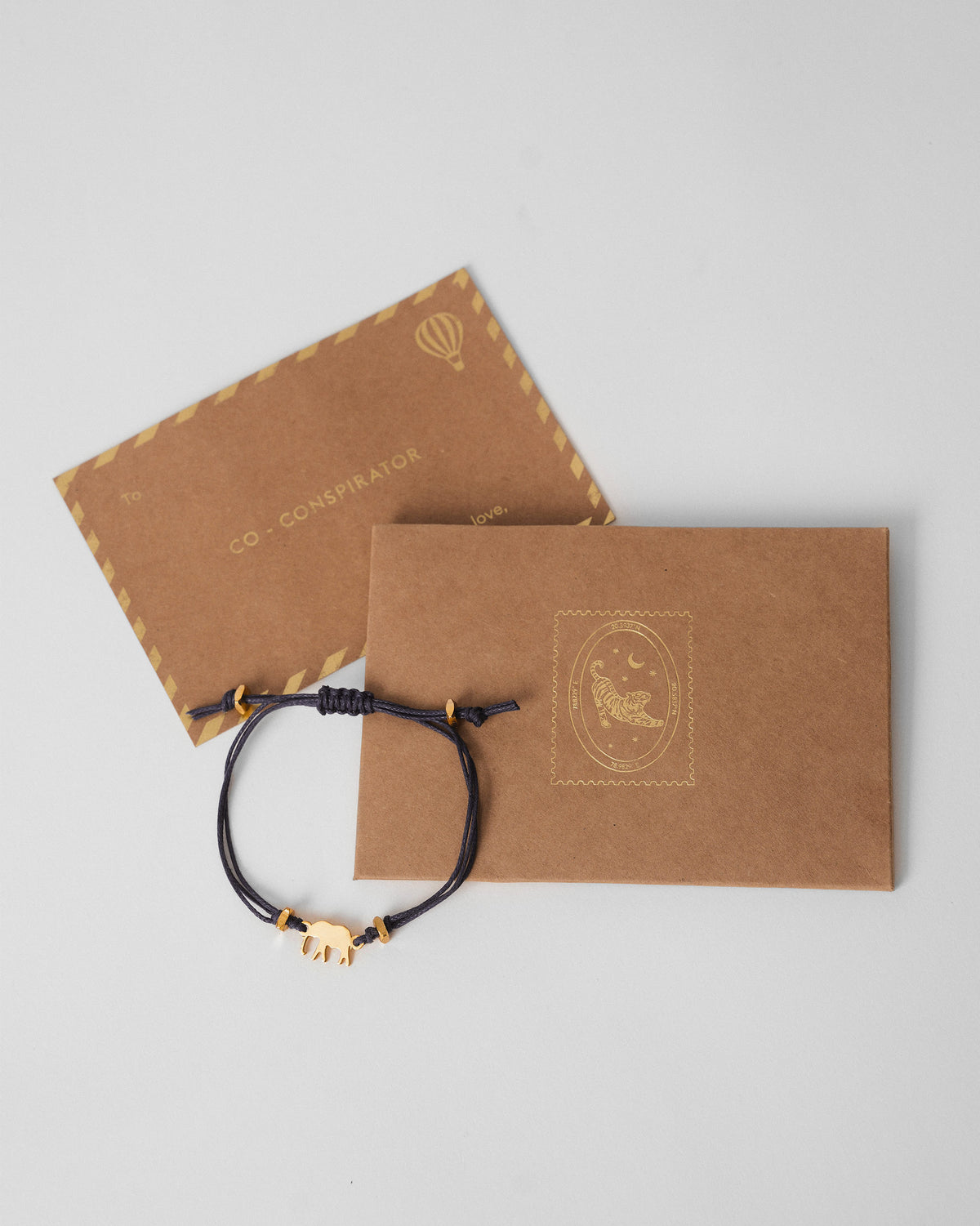 Blue Ele Rakhi beside a kraft gift envelope and card.