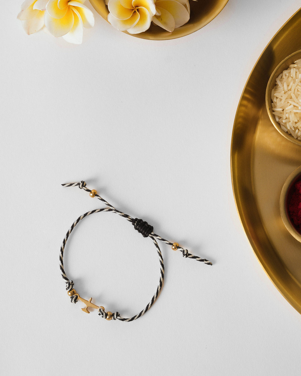 Airplane Rakhi laid flat on white with a gold airplane charm and gold beads.