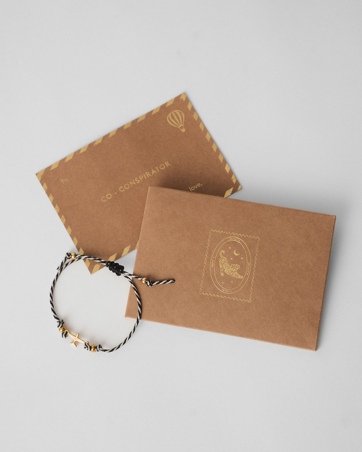 Airplane Rakhi laid beside a kraft envelope on a grey surface.