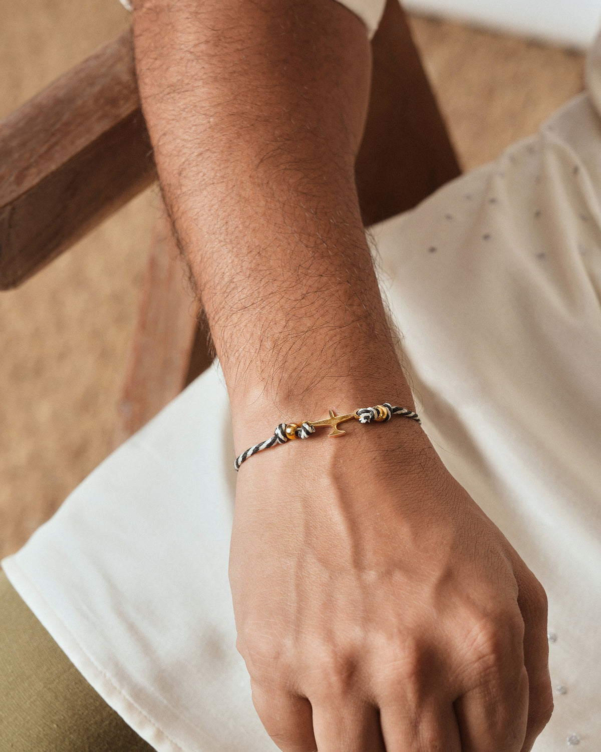 Person wearing Airplane Rakhi on the wrist with a gold airplane charm.