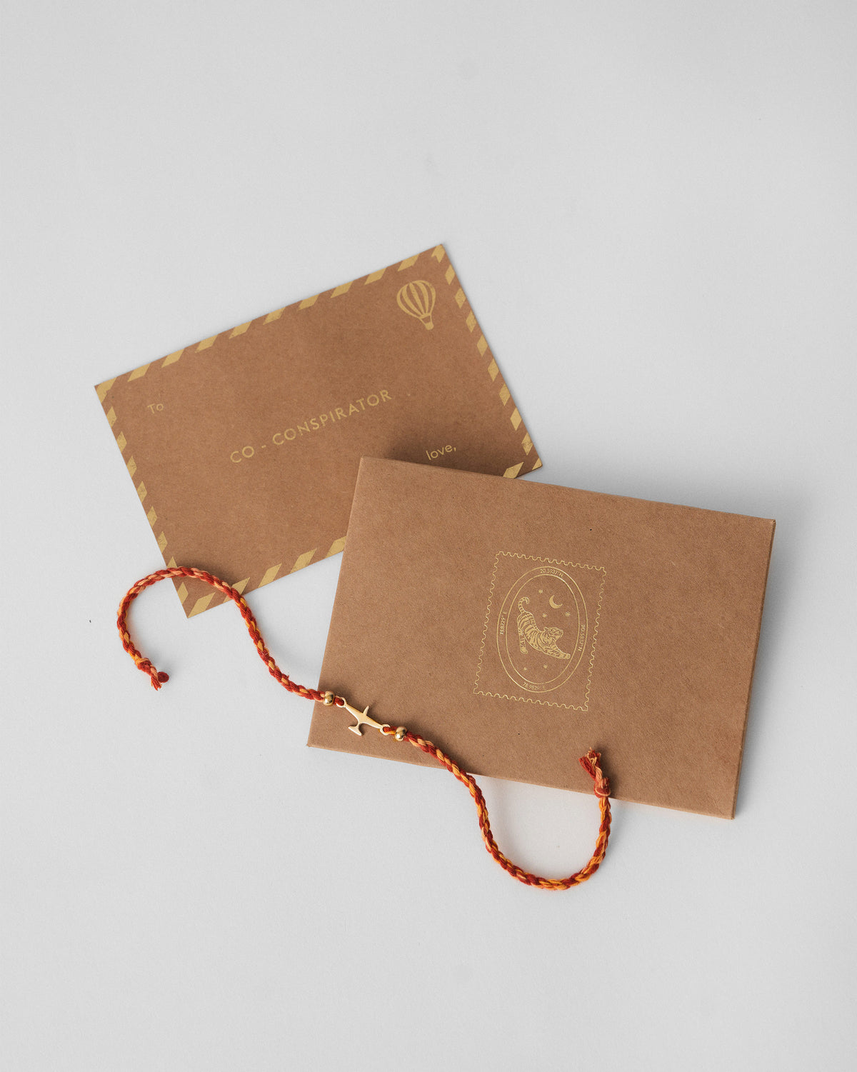 Airplane Rakhi draped across a kraft envelope on a grey surface.