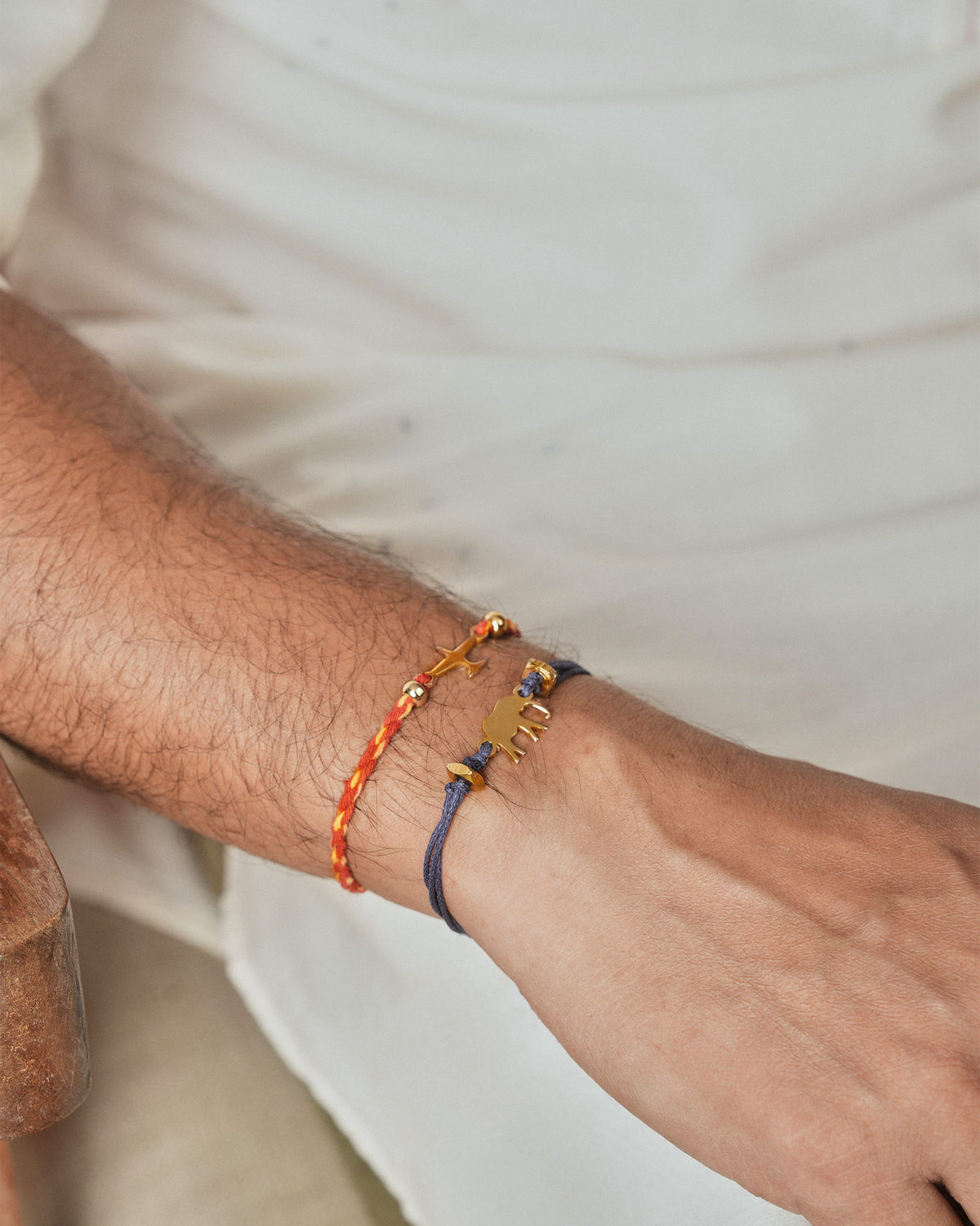 Person wearing Airplane Rakhi in red on the wrist, beside a navy bracelet.