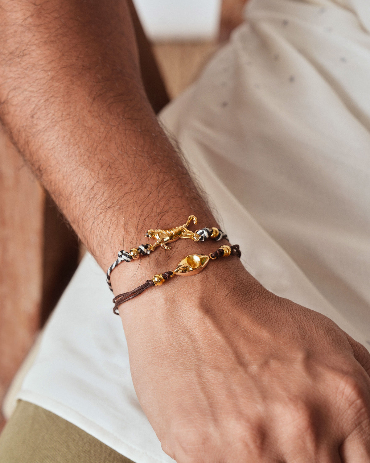 Person wearing a brown Evil Eye Rakhi with a gold charm.