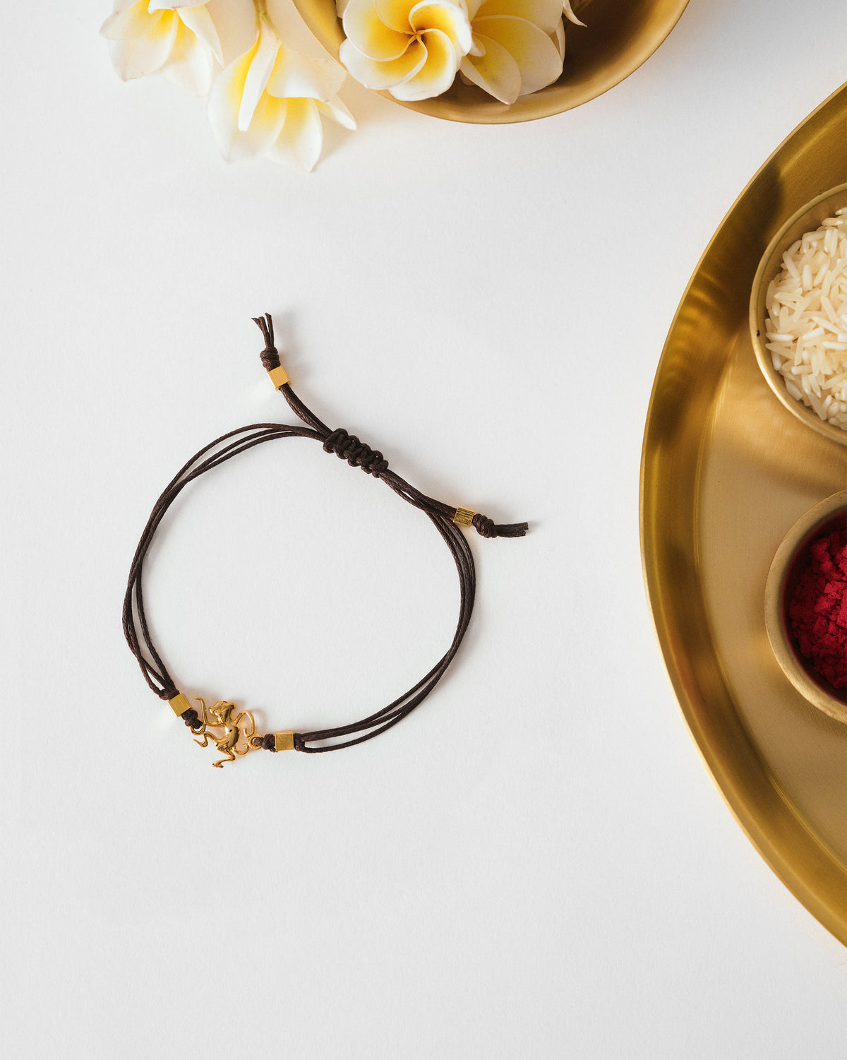 Brown Monkey Rakhi with a gold monkey charm laid flat.