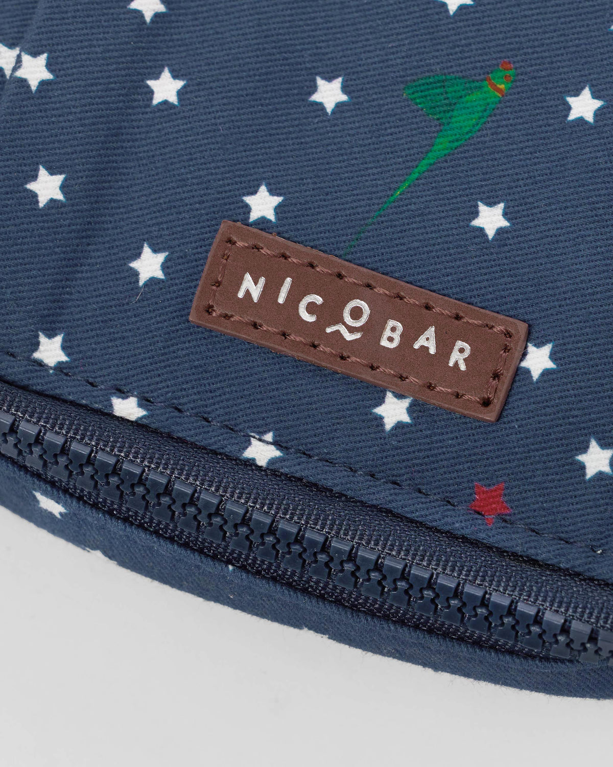 Close-up of the Nicobar leather patch on a navy Gadget Pouch.