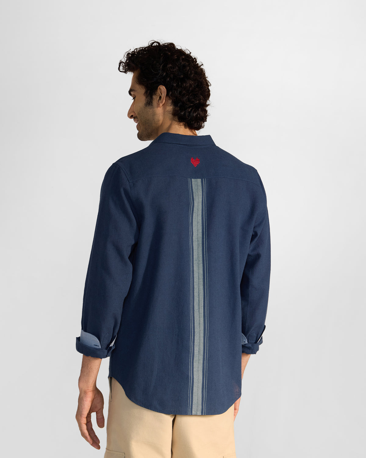 Back of a navy Rewa shirt with a red heart embroidery and center stripe.