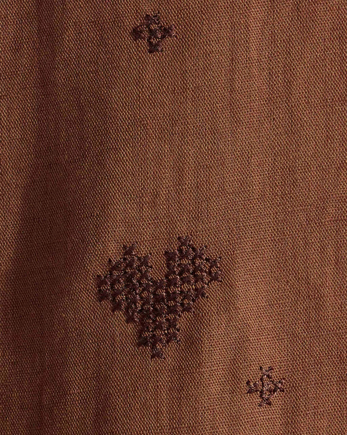 Close-up of dark brown heart embroidery on a Classic Shirt.