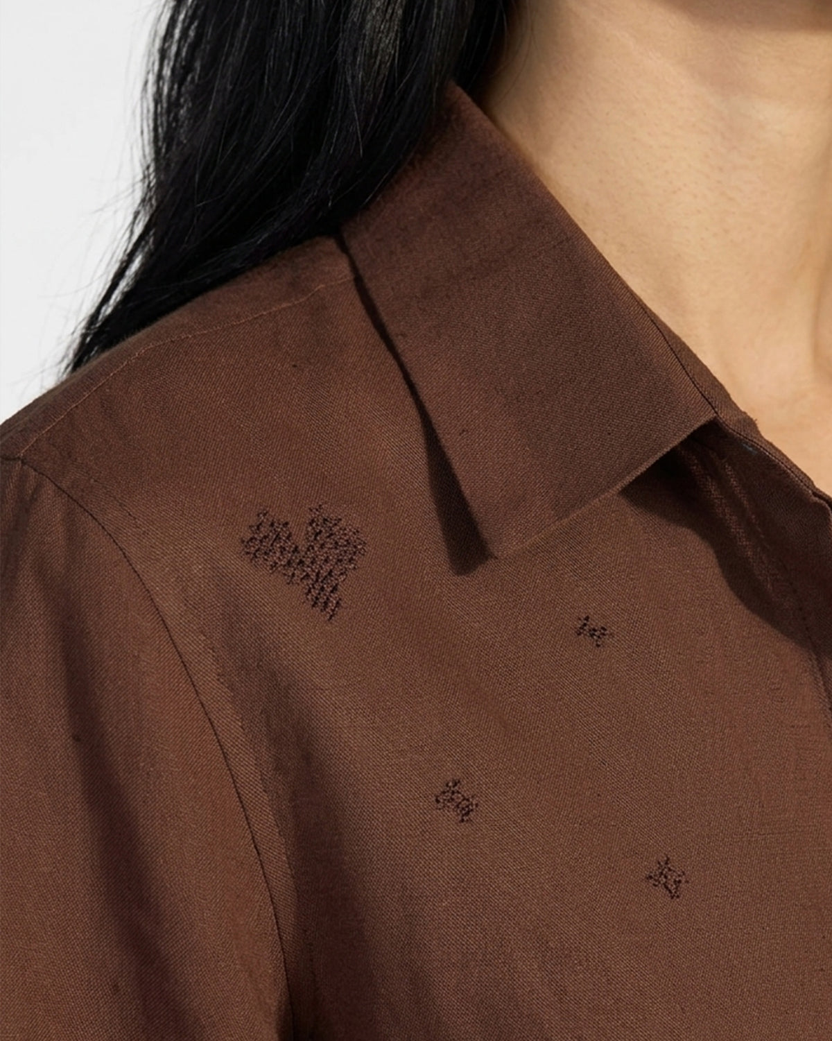 Close-up of embroidered motifs near the collar of a brown Classic Shirt.