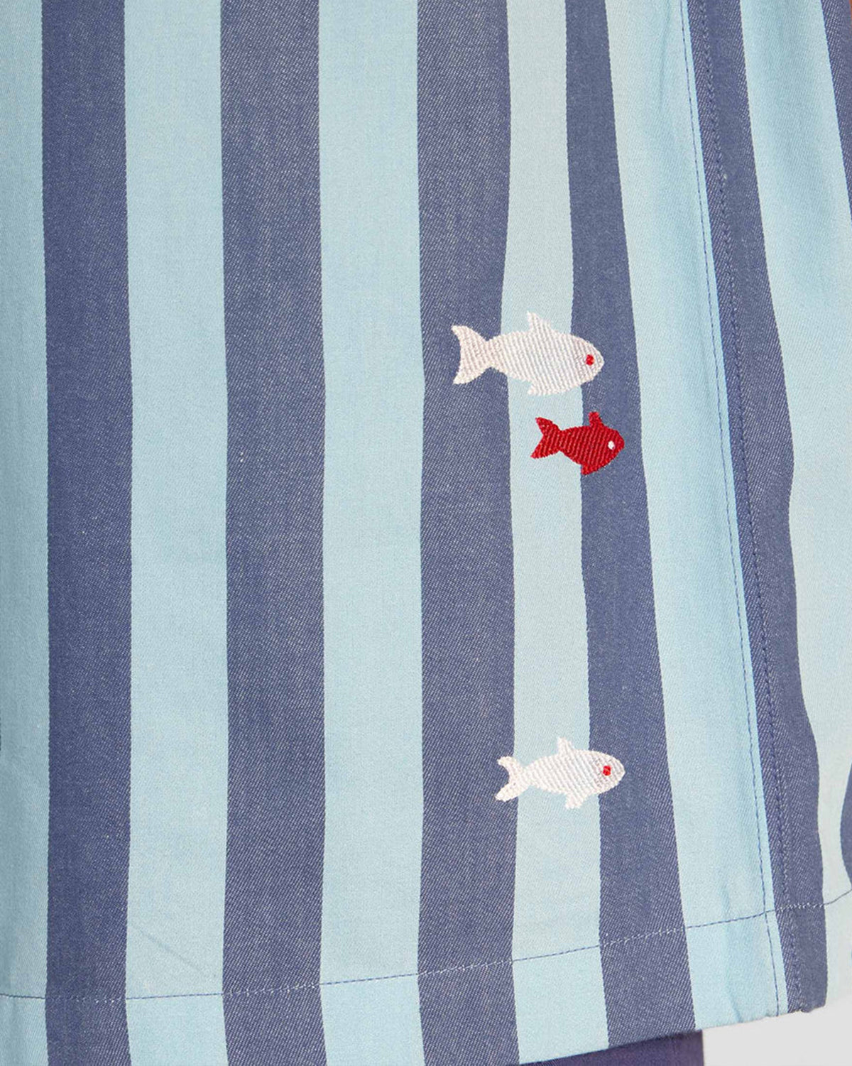 Close-up of blue Nilambar shirt stripes with embroidered fish near the hem.