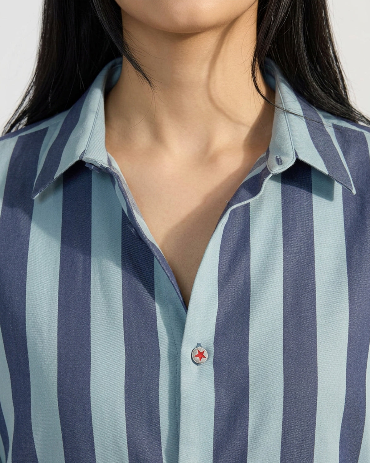 Close-up of a blue striped Nilambar shirt with a red star button.