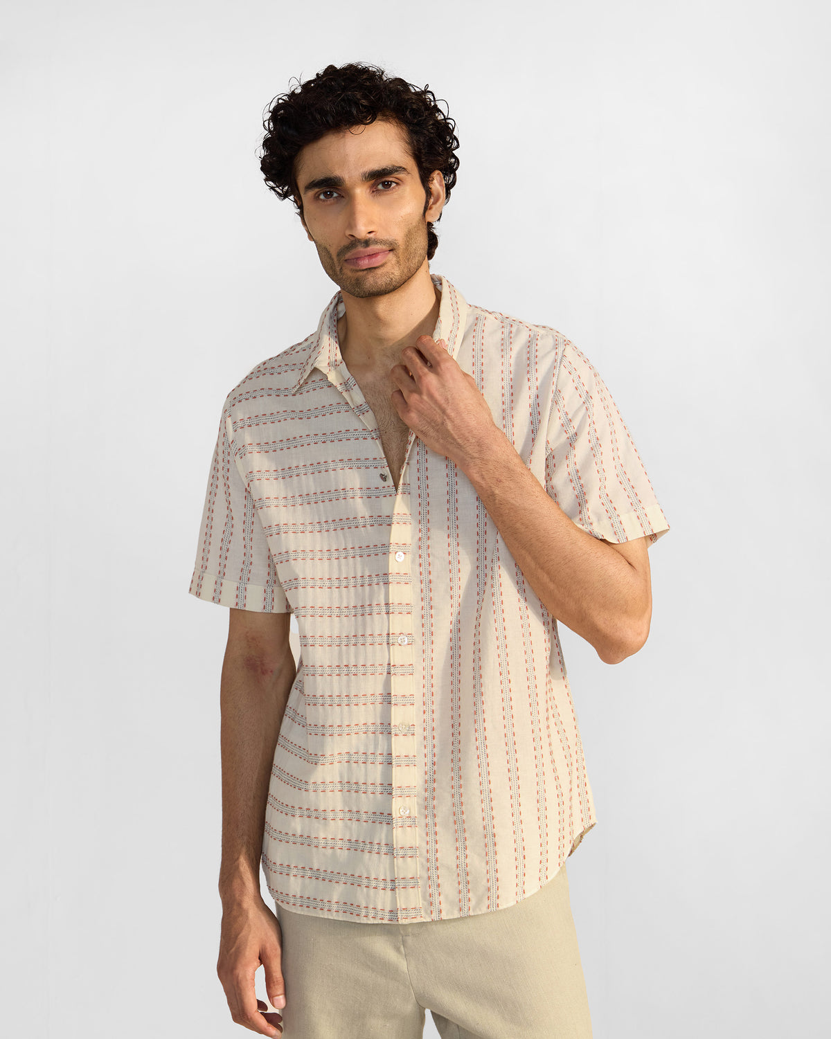 Person wearing an ivory Half Sleeves Shirt with a dashed stripe pattern and pointed collar.