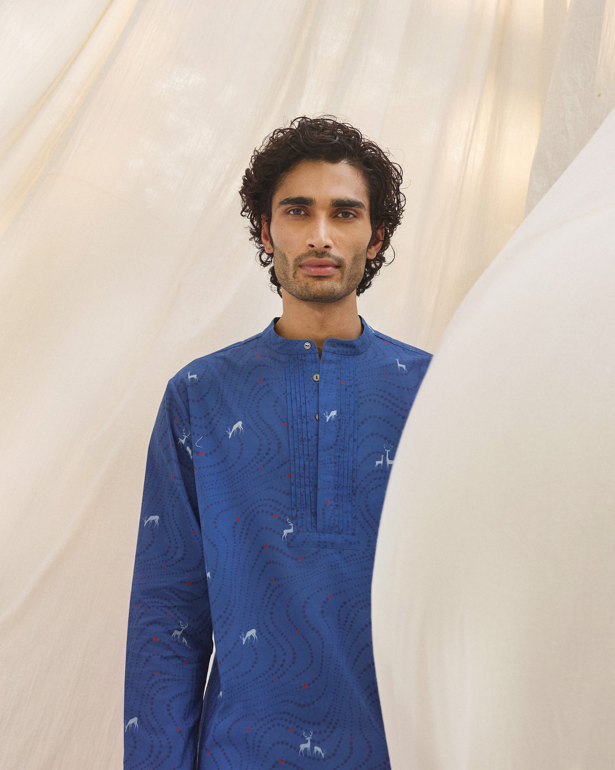 Person wearing a blue Front Pleat kurta with white deer print and chest pleats.