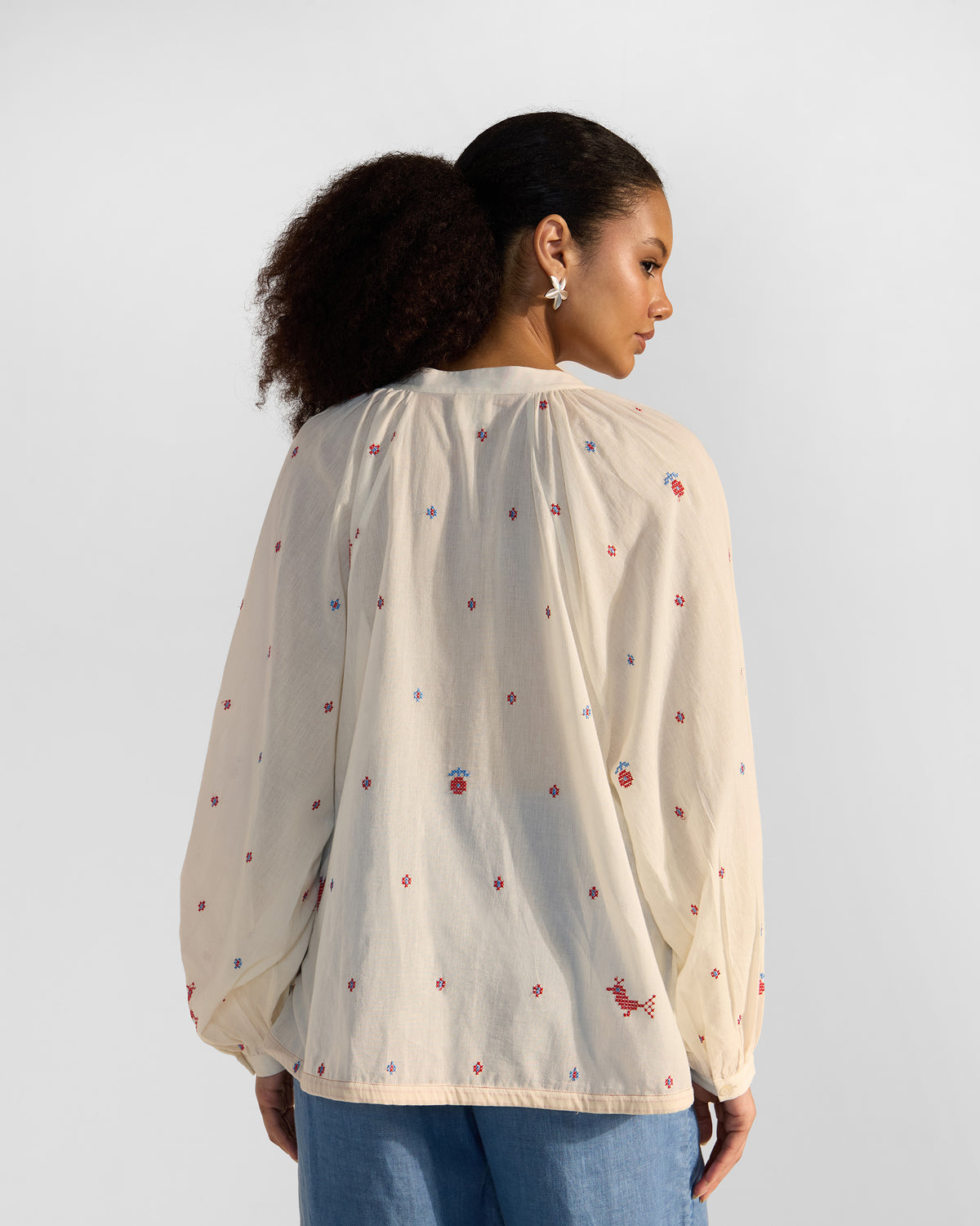 Back of an ivory Tahi top with scattered red embroidery.