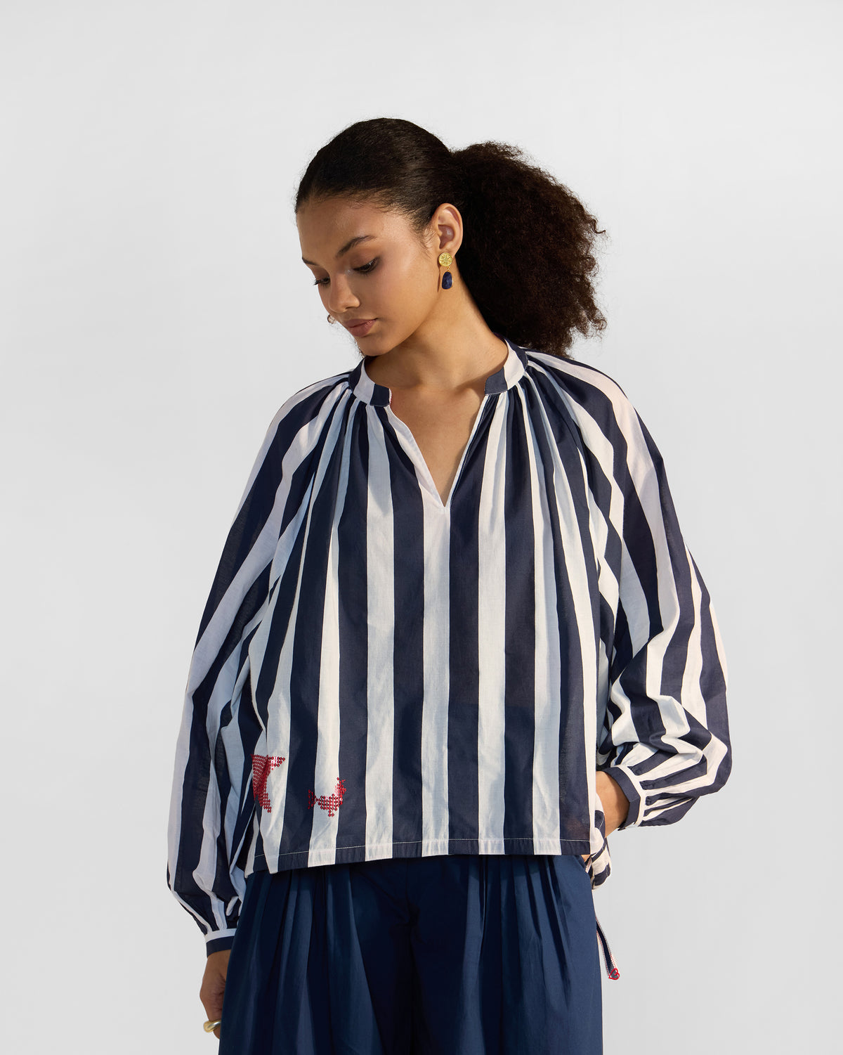 Person wearing a navy and white striped Zaya top with red embroidery.