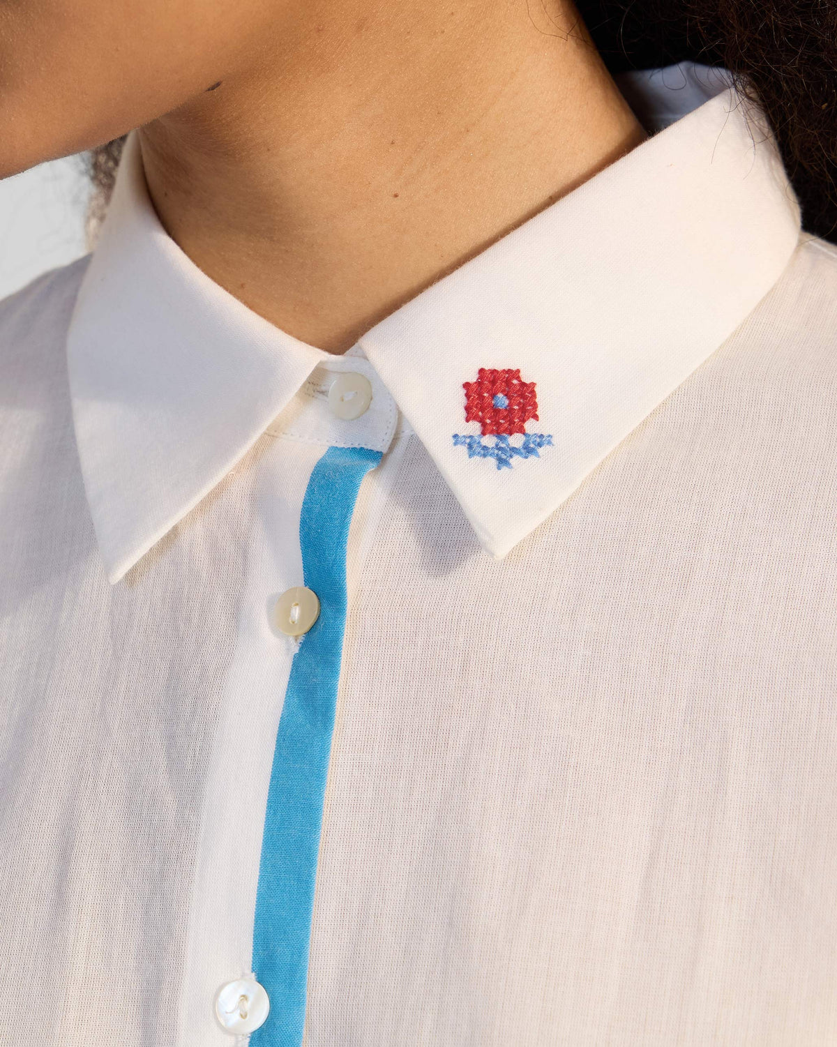 Close-up of an Eira top collar with a red flower and blue trim.
