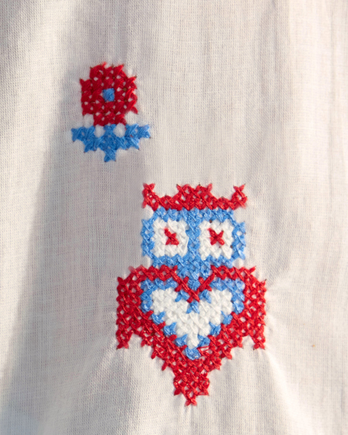 Close-up of an owl embroidery on a white Eira top.
