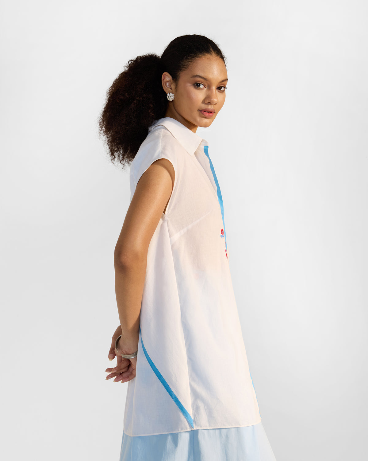 Side view of a white Eira top showing a diagonal blue stripe.