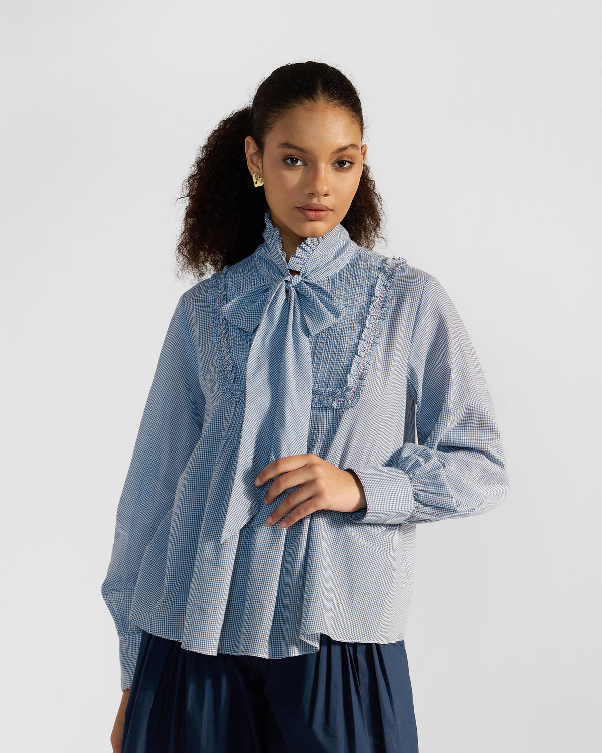 Person wearing a blue check Lona top with a necktie bow.