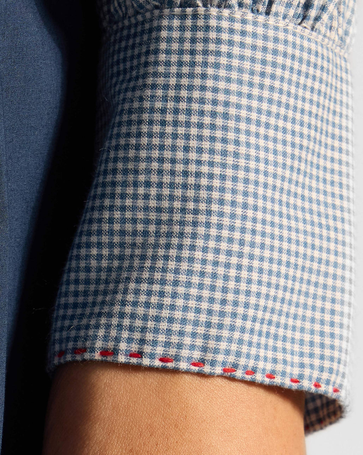 Close-up of red stitching on a blue check Lona top cuff.