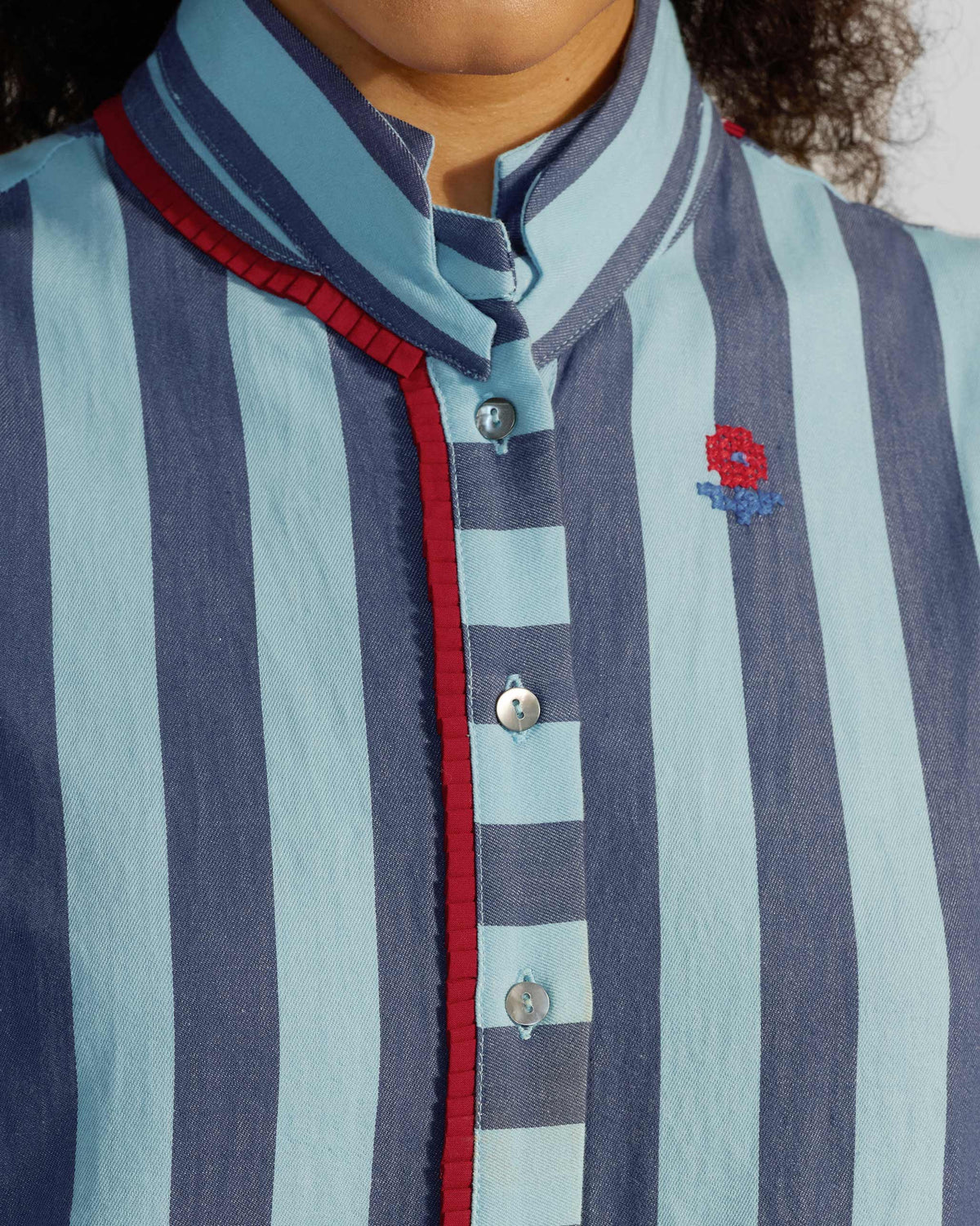 Close-up of a Bargi jumpsuit collar with red trim and a flower motif.