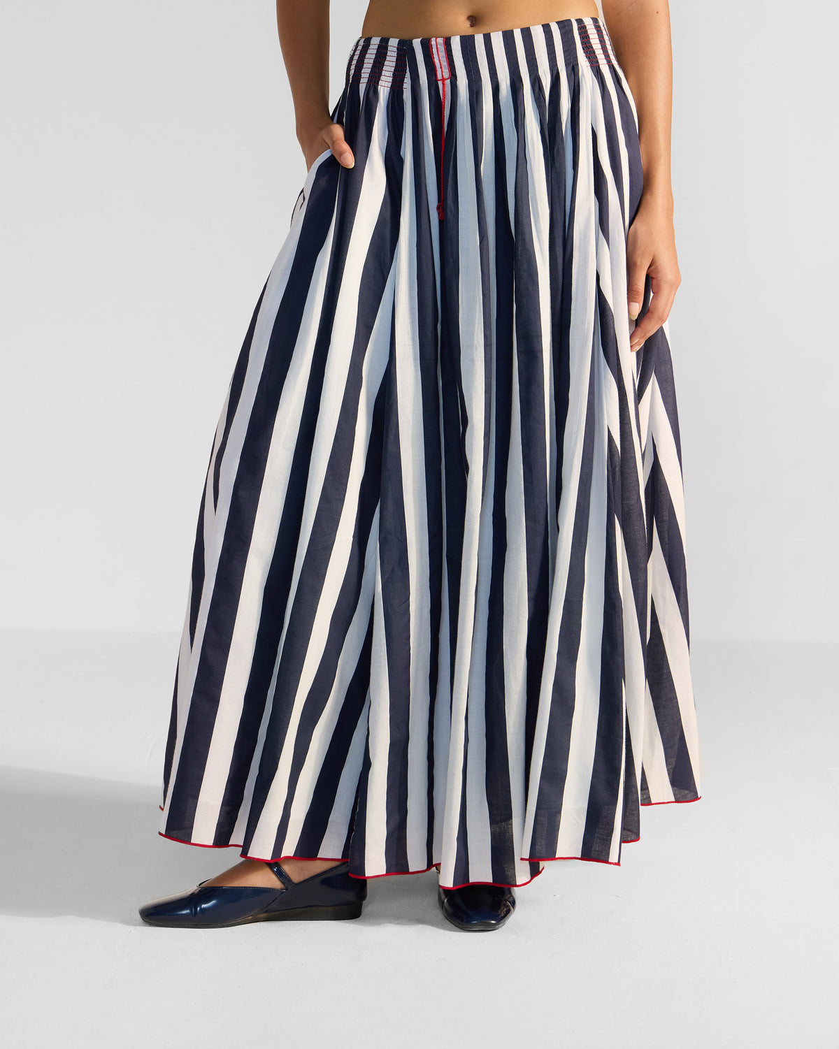 Navy and white striped Reyat skirt with a hand in the side pocket.