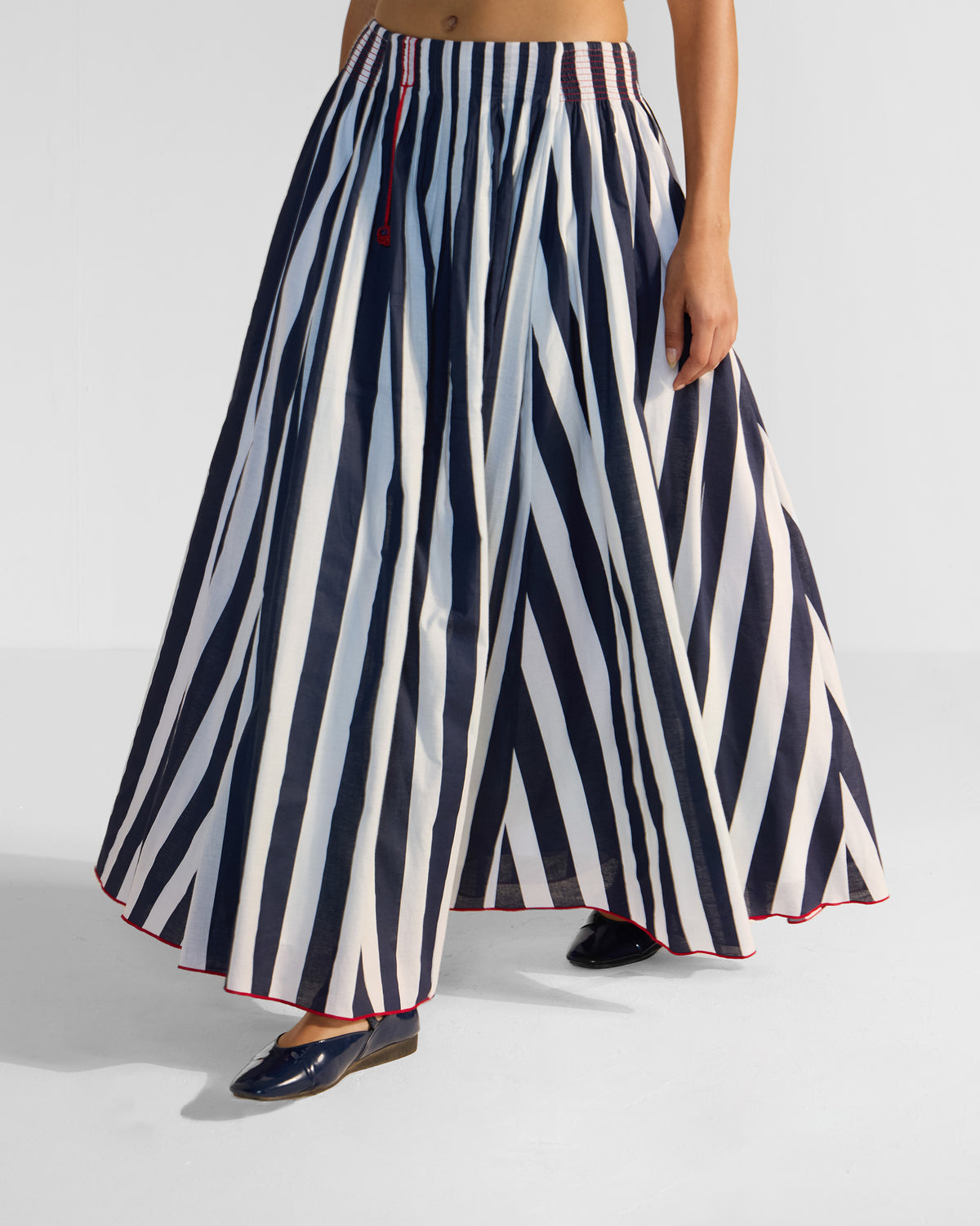 Navy and white striped Reyat skirt with a smocked waist and red drawstring.
