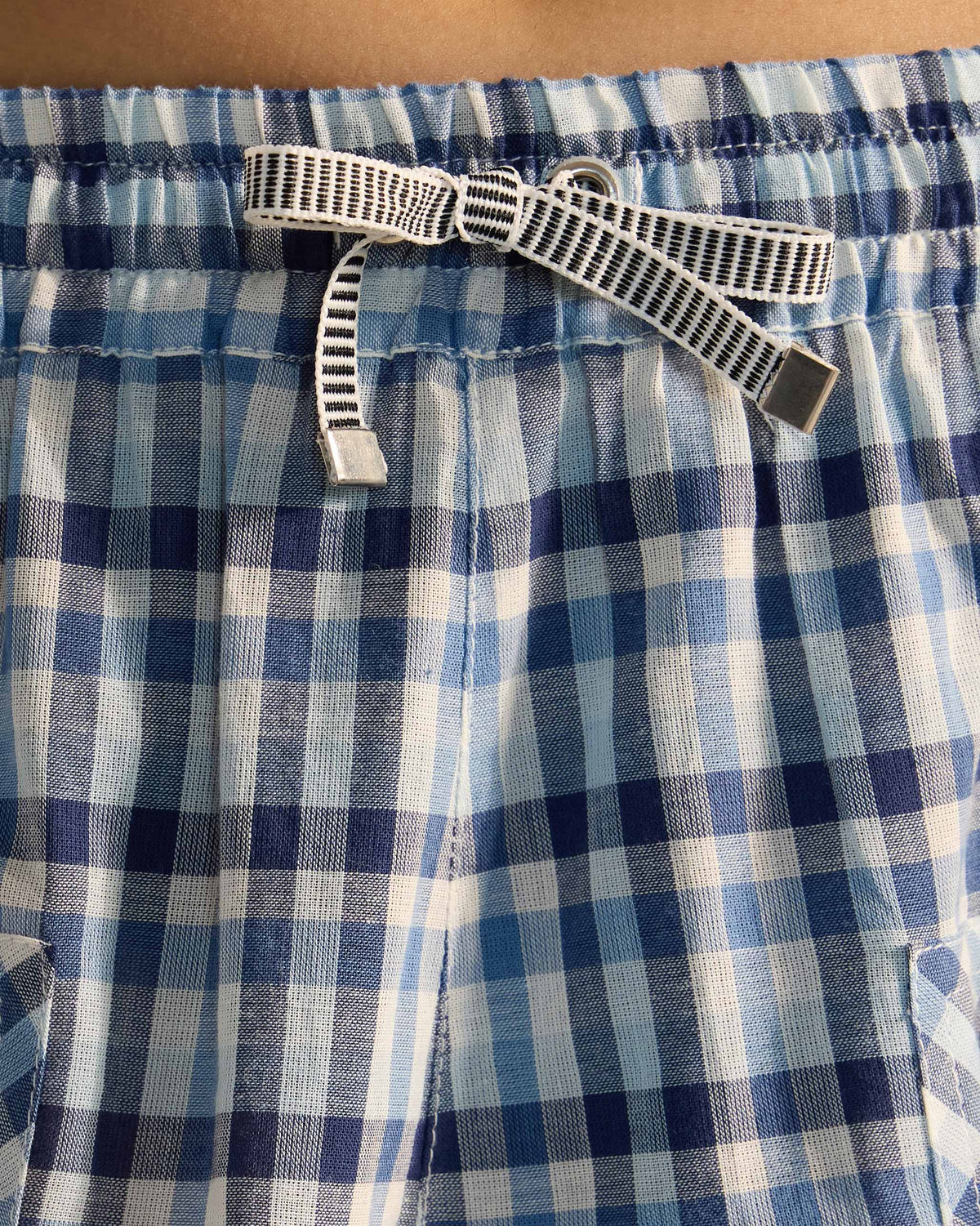 Close-up of the striped drawstring waist on blue and white checked Yoka trousers.
