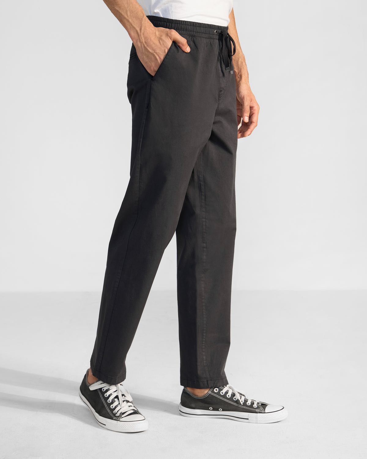 Side view of black Pravah trousers showing the straight leg and side pocket.