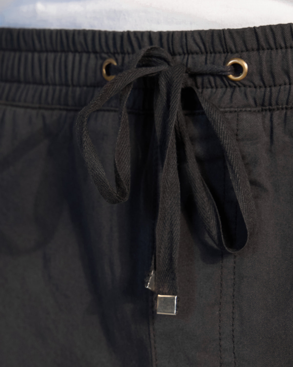 Close-up of a black Pravah trouser drawstring waistband with metal tips.