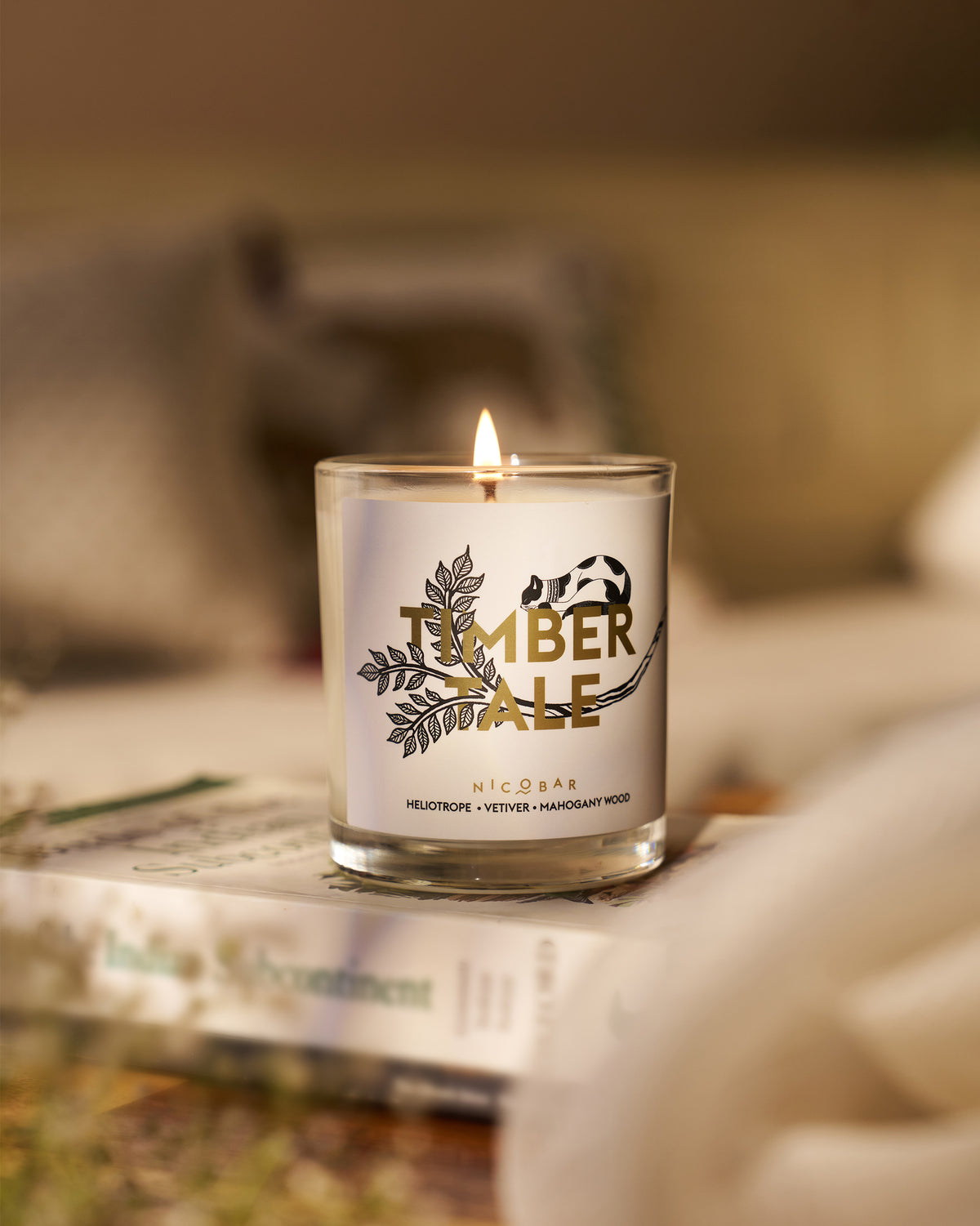 Timbertale Candle burning in its glass, with the flame visible.