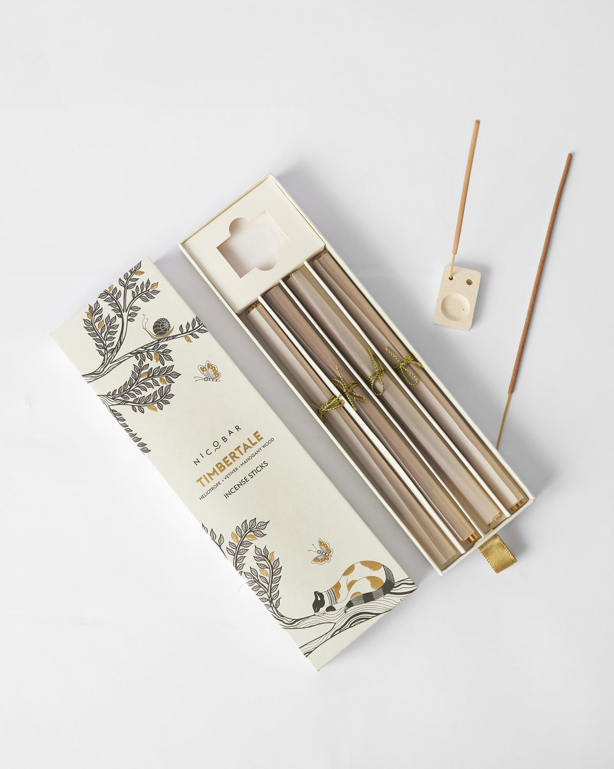 Open box of Timbertale Incense Sticks with a ceramic holder and loose sticks beside it.