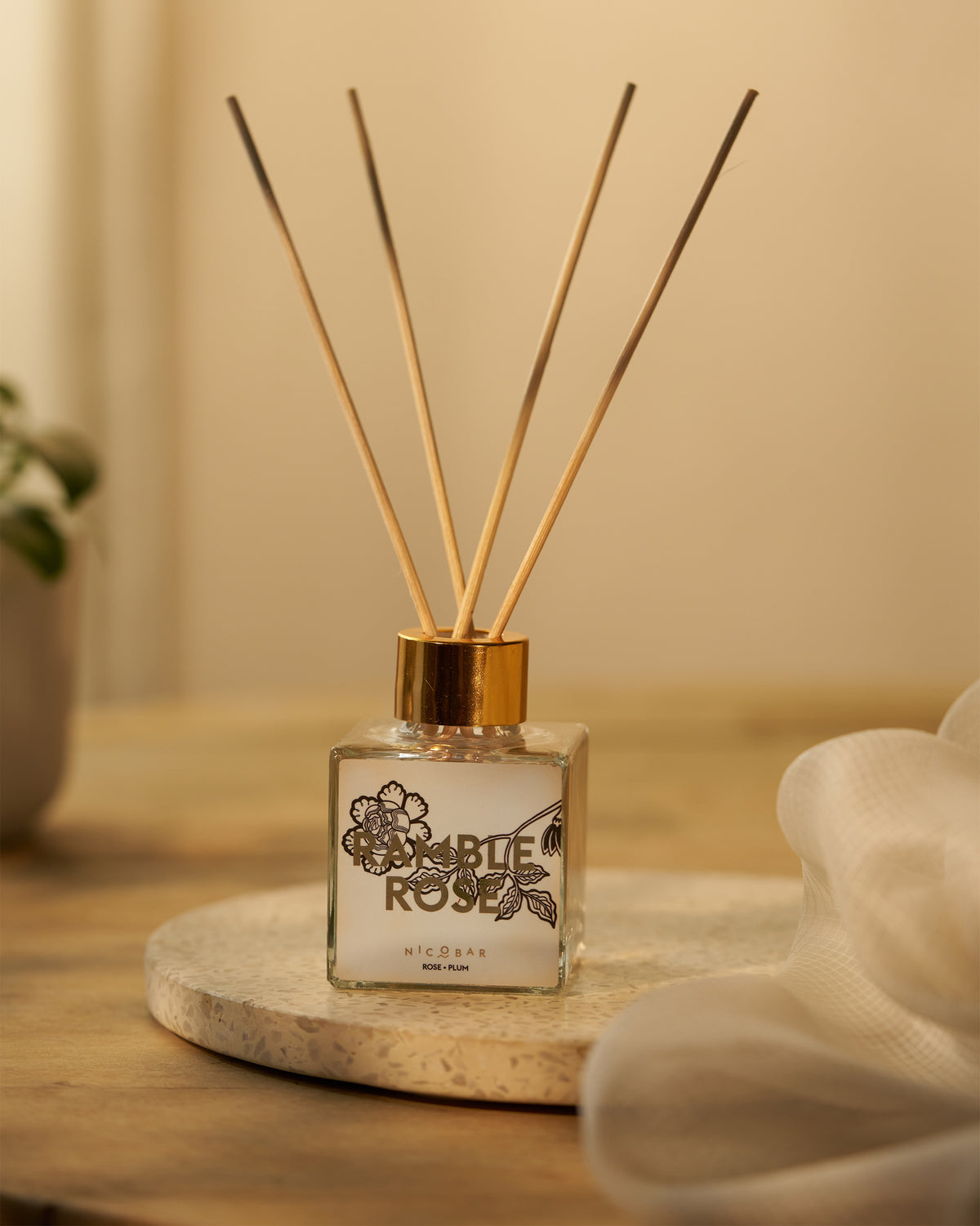 Ramblerose reed diffuser with reeds standing up from the gold cap.