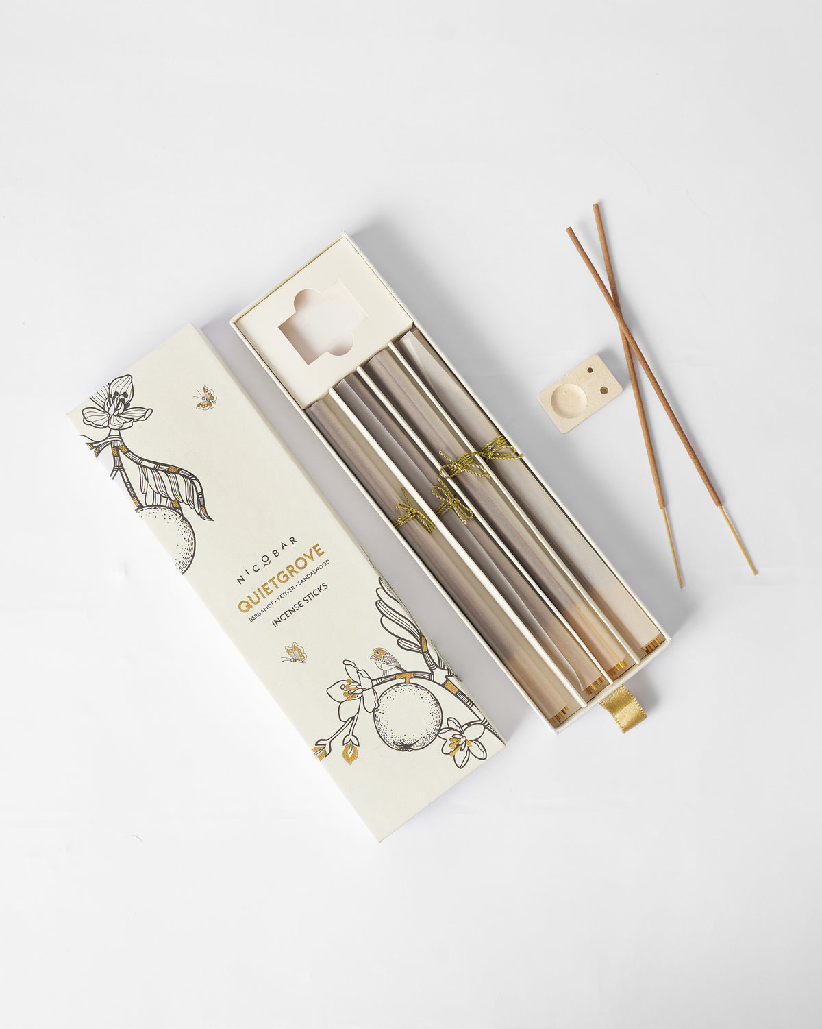 Quiet Grove Incense Sticks laid out beside their open box and a small holder.
