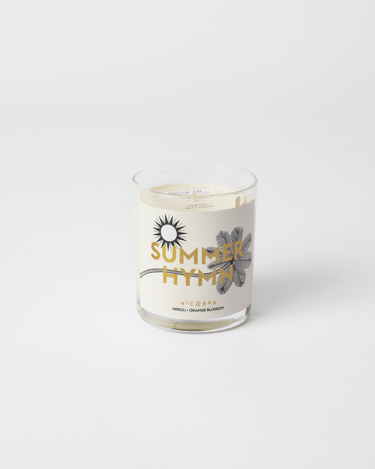 Summerhymn candle in clear glass, unlit, with a sun and leaf motif on the label.