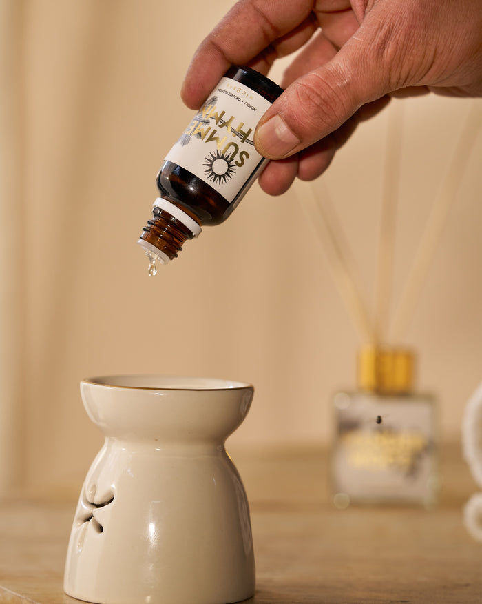 Summerhymn oil vial dropping neroli oil into a ceramic burner.