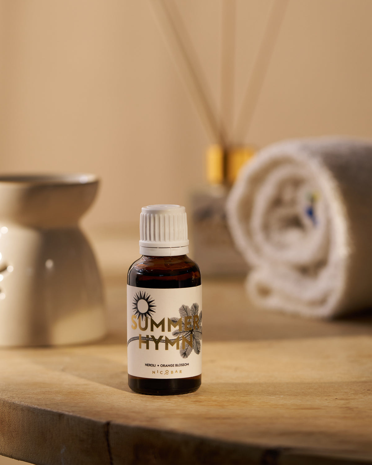 Summerhymn oil vial standing on wood among spa accessories.