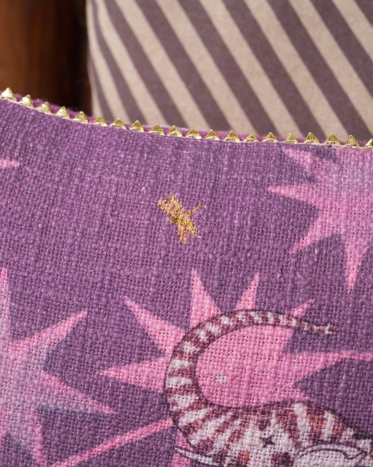 Close-up of a Tusk Bloom Cushion Cover edge with gold trim and a small gold motif.