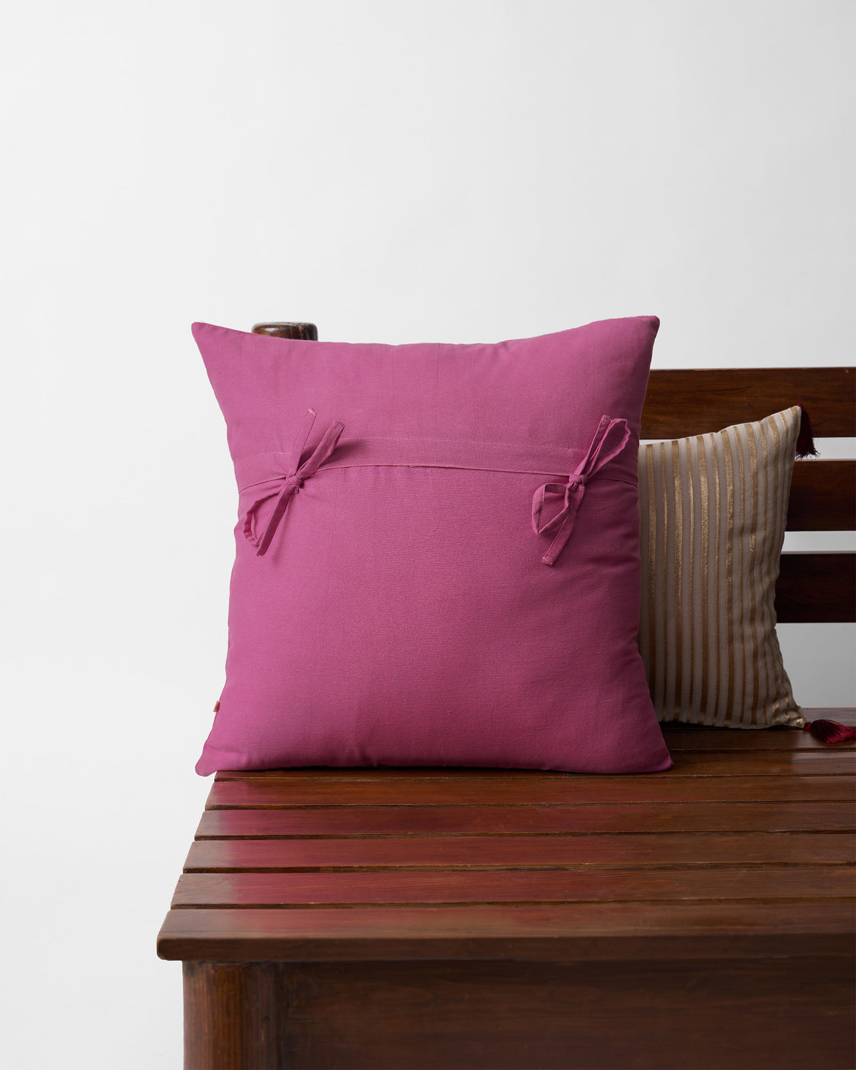 Back of a pink Mogra cushion cover with two tied bows.